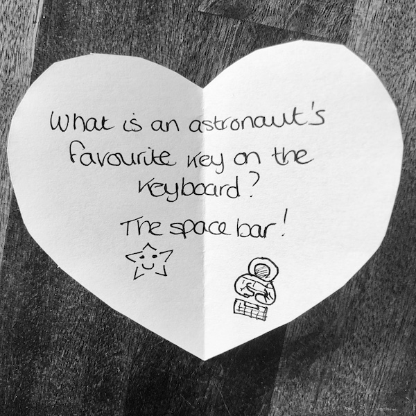 Science joke for kids on a white paper heart: What is an astronaut’s favourite key on the keyboard? The space bar!