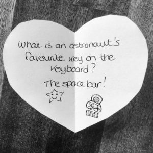 Science joke for kids on a white paper heart: What is an astronaut's favourite key on the keyboard? The space bar!