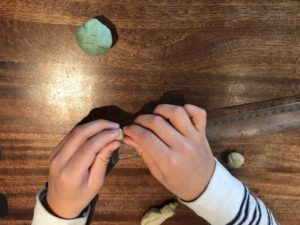 A child measuring balls of playdough to find out the relative sizes of Earth and Mars